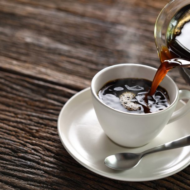 Pouring coffee with smoke on a cup on wooden background